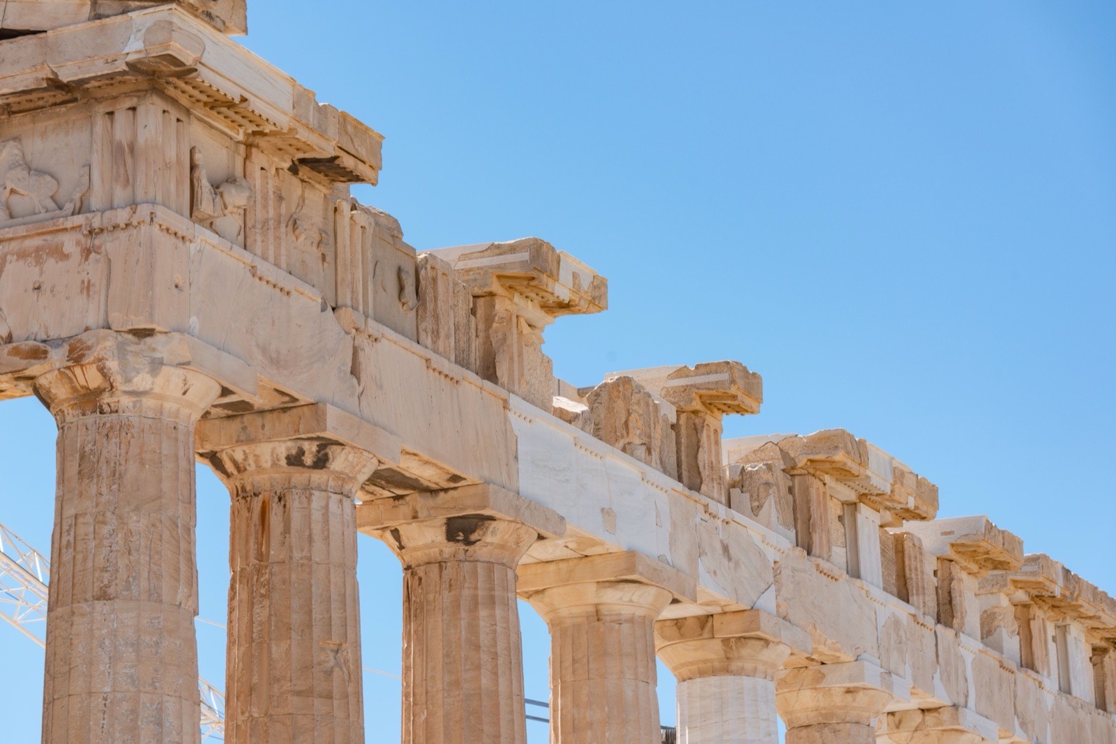 Close-up of the Parthenon columns in Athens, Greece, against a clear summer sky.