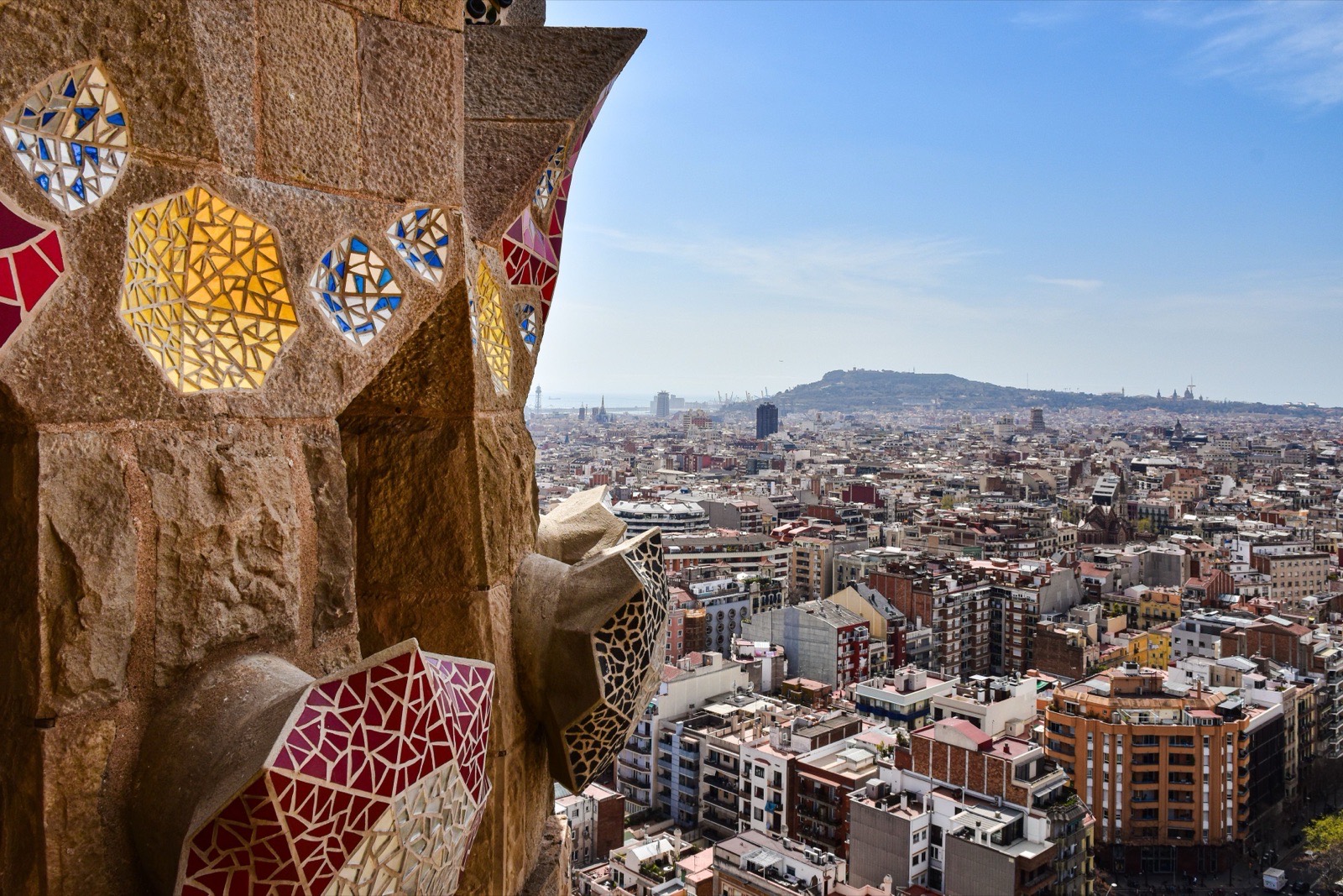 View from a mosaic tower overlooking the vibrant cityscape of Barcelona, capturing architectural beauty and urban life.