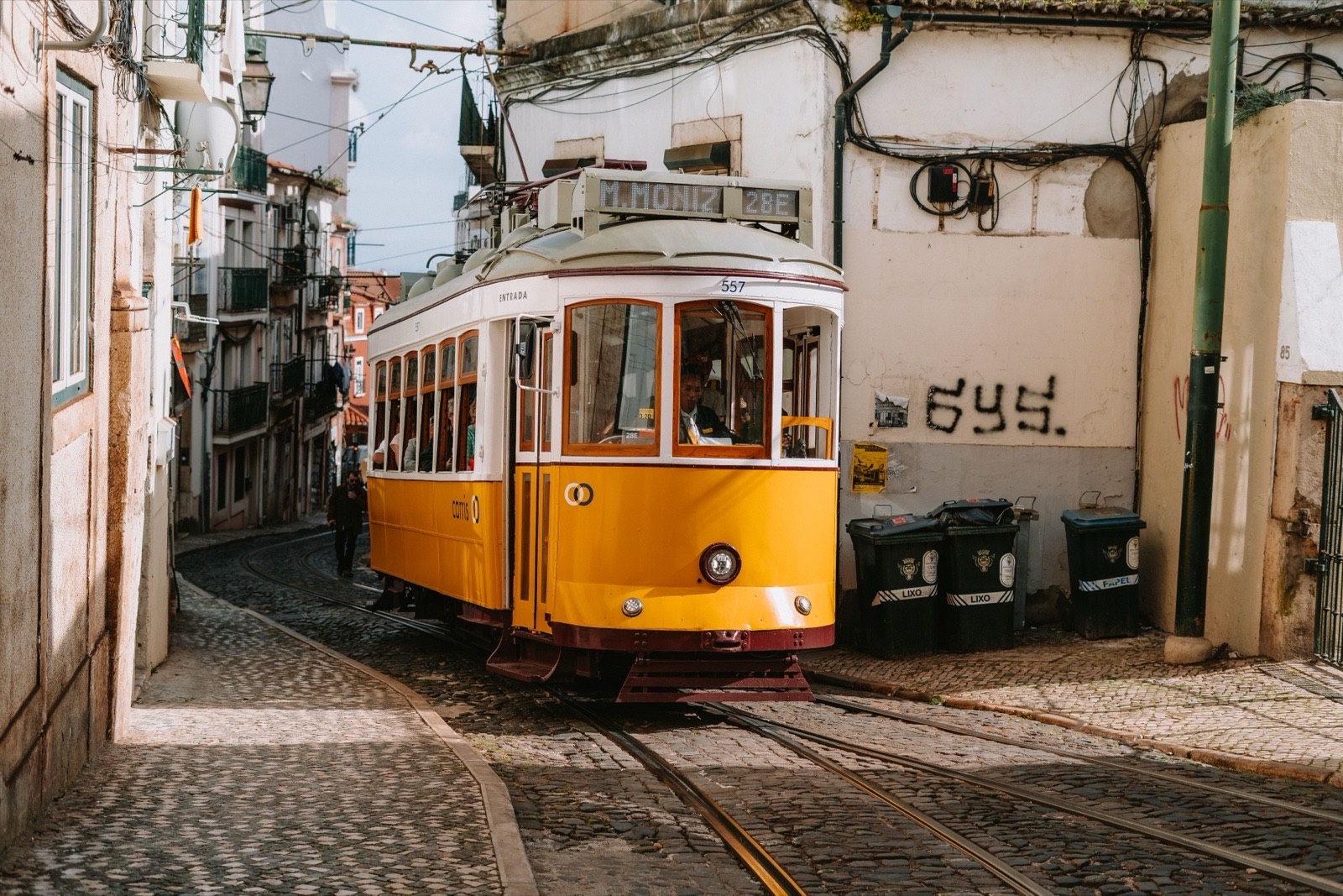 Historic yellow tram on Lisbon's cobblestone street, capturing a classic European scene.