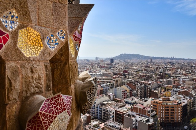 View from a mosaic tower overlooking the vibrant cityscape of Barcelona, capturing architectural beauty and urban life.