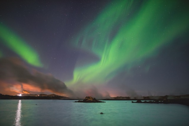 Captivating northern lights dancing over the serene lake in Keflavik, Iceland.