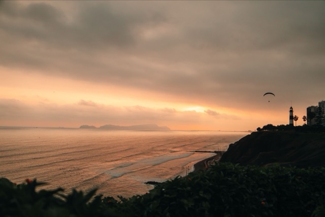 Breathtaking sunset view with a paraglider over the Pacific from Lima, Peru.