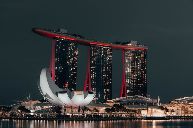 Dramatic night view of Marina Bay Sands, Singapore, with glowing cityscape and reflection.